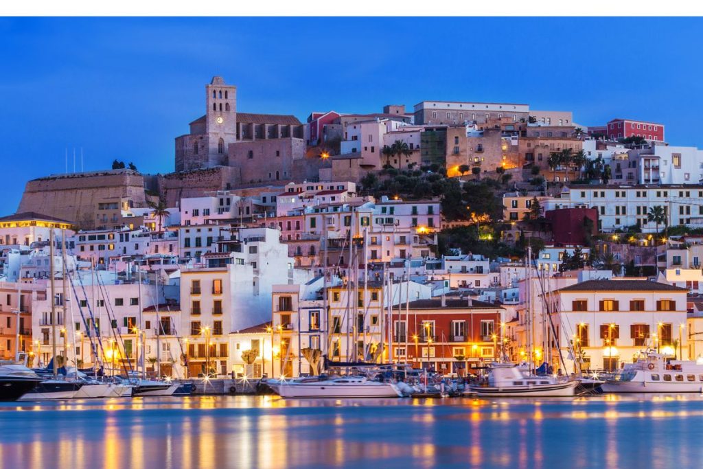 Ibiza Town and Dalt Vila skyline at dusk with reflections on the water